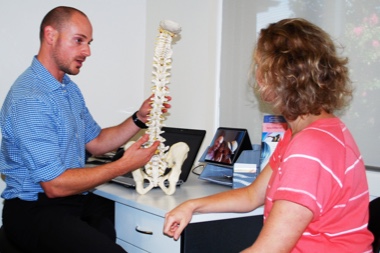Dr Daniel Grynberg showing a patient a model of the spine